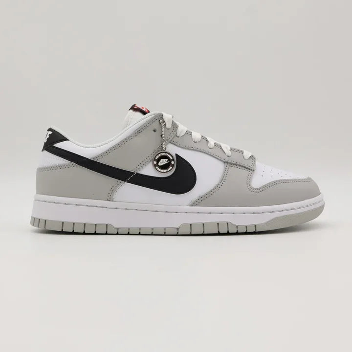 Tenis Cinza Nike Dunk Low de Lado com moeda